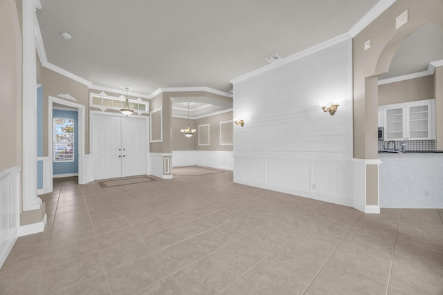 198 Magnolia Lakes Blvd, Port Saint Lucie, FL 34986 - unfurnished living room with a decorative wall, tile patterned floors, crown molding, arched walkways, and wainscoting