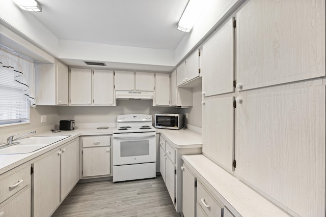 2950 SE Ocean Blvd Unit 9-5, Stuart, FL 34996 - kitchen with electric stove, under cabinet range hood, stainless steel microwave, a sink, and light wood-type flooring