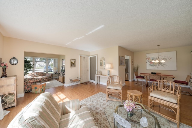 14240 Nesting Way Unit D, Delray Beach, FL 33484 - living area featuring a chandelier, light wood-style flooring, a textured ceiling, and baseboards