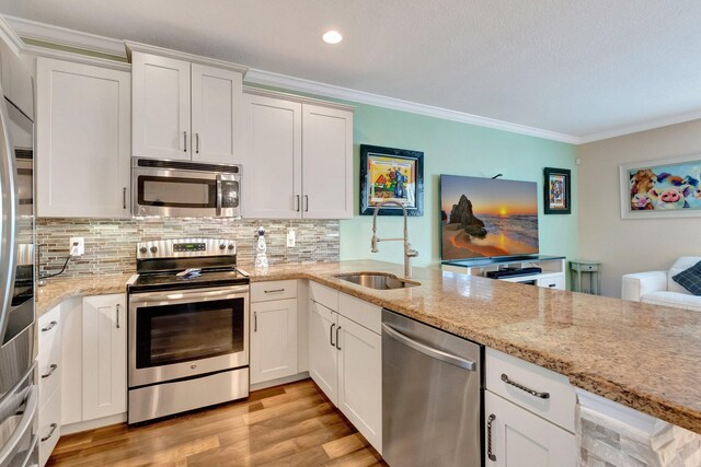 5014 Manchia Dr, Lake Worth, FL 33463 - kitchen with appliances with stainless steel finishes, a sink, ornamental molding, backsplash, and light stone countertops