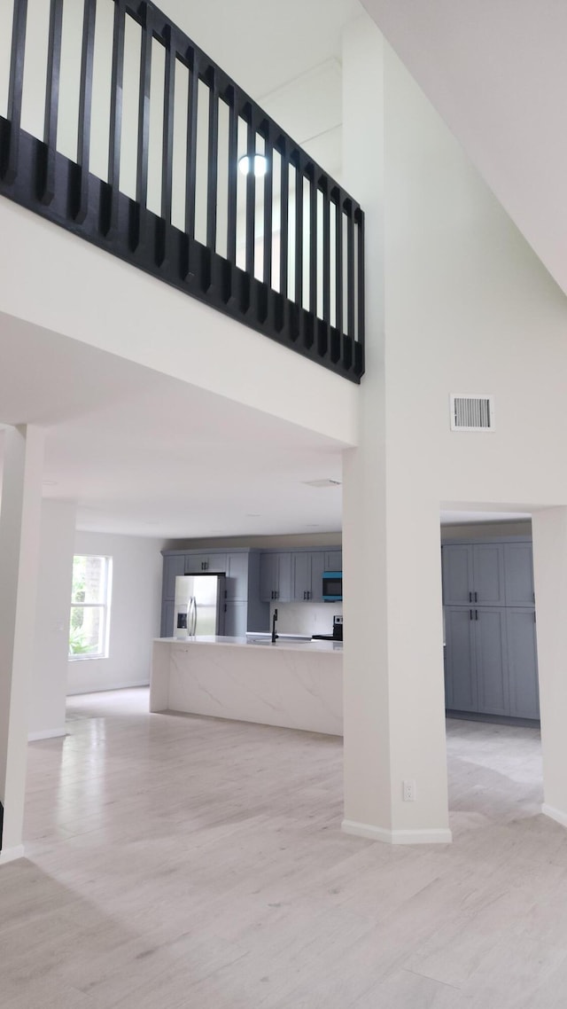 2012 White Coral Ct, Wellington, FL 33414 - unfurnished living room featuring a high ceiling, baseboards, light wood-type flooring, and a sink