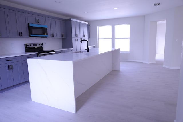 2012 White Coral Ct, Wellington, FL 33414 - kitchen with appliances with stainless steel finishes, a sink, a large island, light wood finished floors, and light stone counters