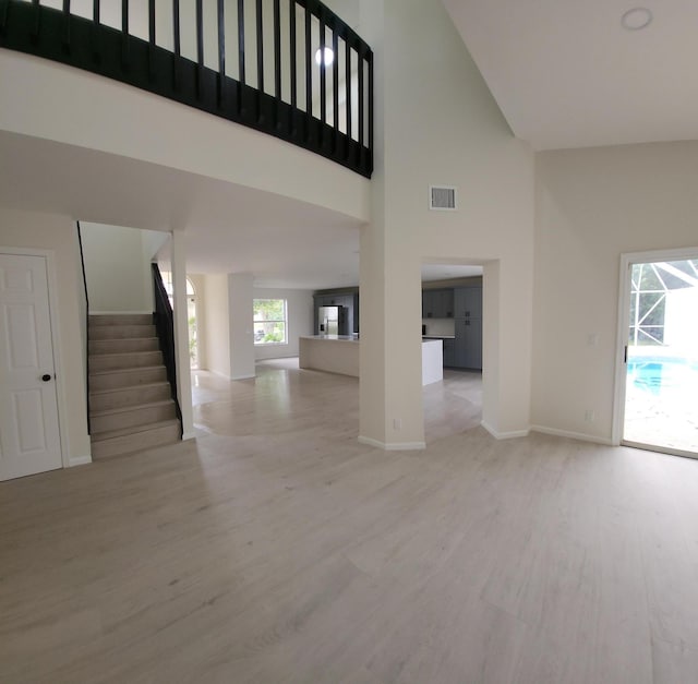 2012 White Coral Ct, Wellington, FL 33414 - unfurnished living room featuring a high ceiling, wood finished floors, stairs, and baseboards