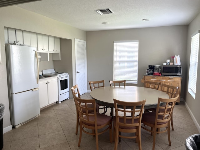 308 Golfview Rd Unit 107, North Palm Beach, FL 33408 - dining area featuring light tile patterned floors, a textured ceiling, and baseboards