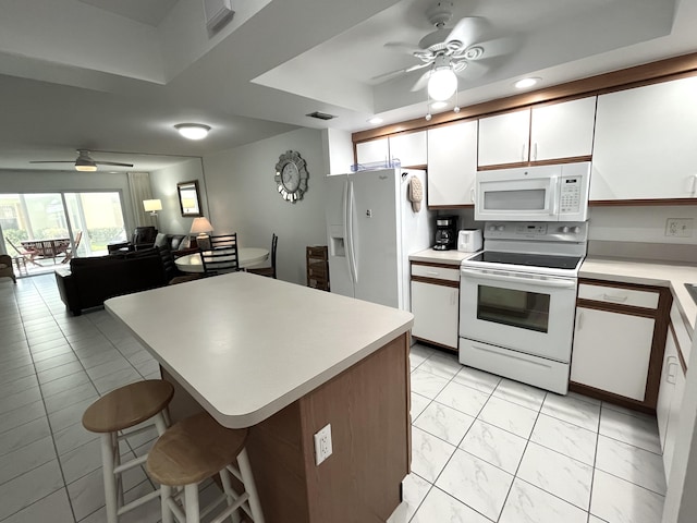 308 Golfview Rd Unit 107, North Palm Beach, FL 33408 - kitchen featuring white appliances, ceiling fan, white cabinetry, light countertops, and a kitchen bar