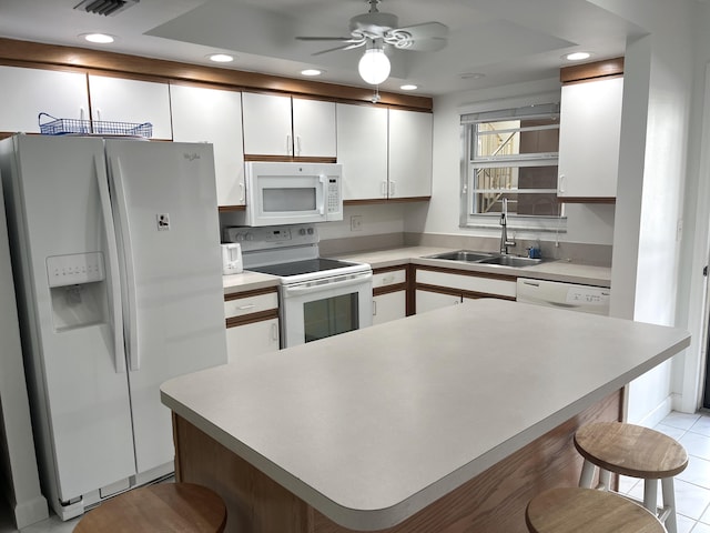 308 Golfview Rd Unit 107, North Palm Beach, FL 33408 - kitchen with white appliances, a sink, white cabinets, a breakfast bar, and a ceiling fan