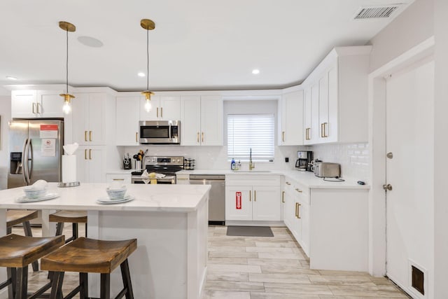 513 Curlew Rd, Delray Beach, FL 33444 - kitchen featuring stainless steel appliances, a sink, a kitchen breakfast bar, white cabinetry, and a center island