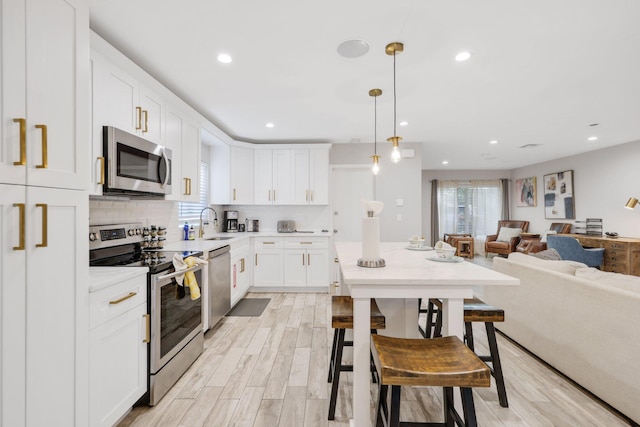 513 Curlew Rd, Delray Beach, FL 33444 - kitchen with appliances with stainless steel finishes, open floor plan, a sink, light countertops, and white cabinetry
