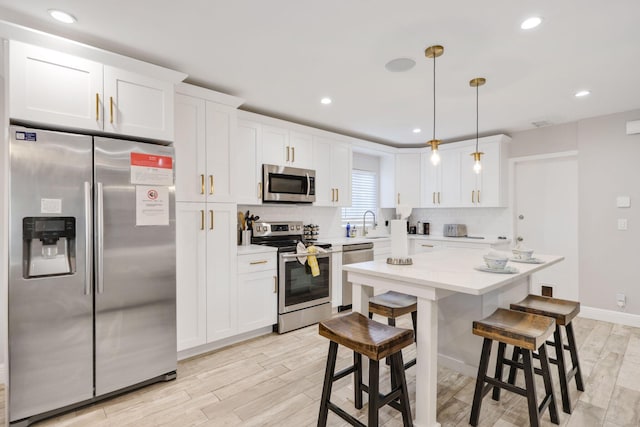 513 Curlew Rd, Delray Beach, FL 33444 - kitchen featuring stainless steel appliances, light wood-style floors, a breakfast bar area, white cabinets, and light countertops