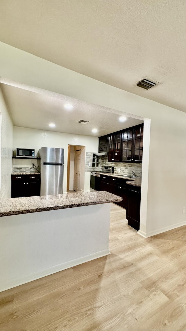629 Troy Blvd, West Palm Beach, FL 33409 - kitchen with stainless steel appliances, light wood finished floors, decorative backsplash, light stone countertops, and glass insert cabinets