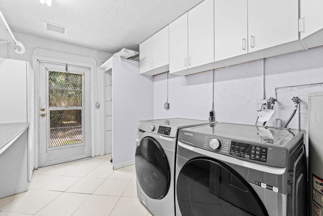 3187 Buccaneer Rd, Lake Worth, FL 33462 - laundry area featuring cabinet space, washer and clothes dryer, light tile patterned flooring, and a textured ceiling