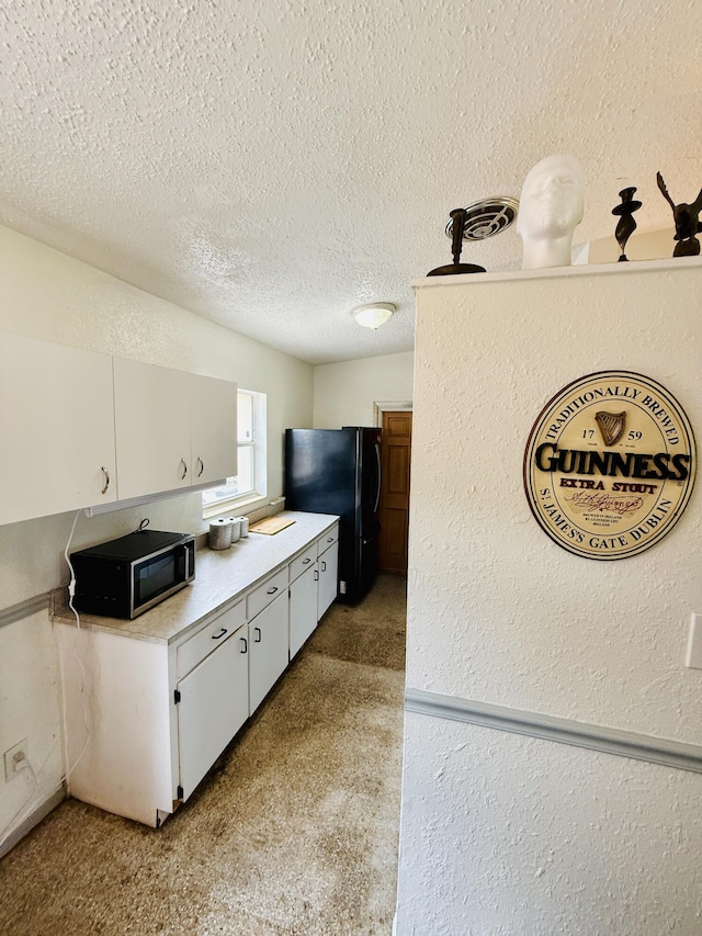 3901 Neptune Dr SE, Saint Petersburg, FL 33705 - kitchen featuring freestanding refrigerator, light countertops, a textured ceiling, white cabinets, and a textured wall