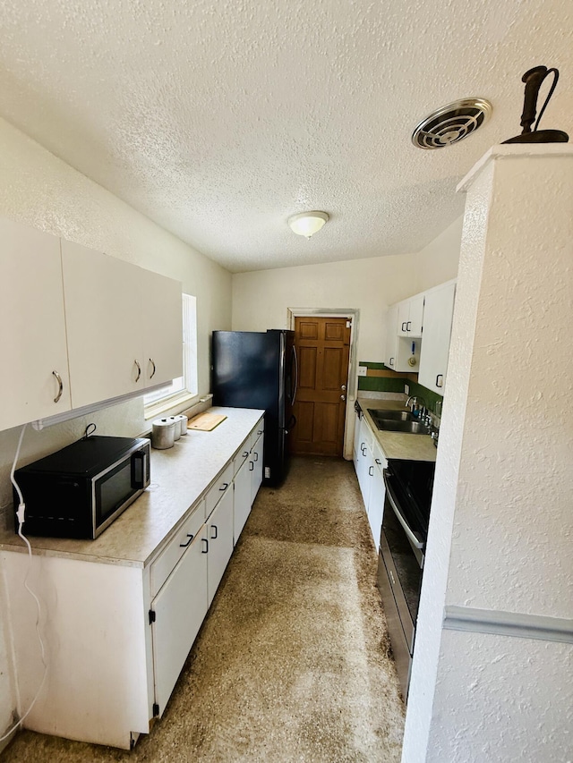 3901 Neptune Dr SE, Saint Petersburg, FL 33705 - kitchen featuring black microwave, a sink, freestanding refrigerator, white cabinets, and light countertops