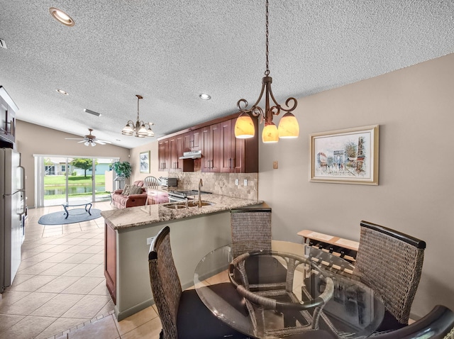 6287 Grand Cypress Cir, Lake Worth, FL 33463 - kitchen with a chandelier, freestanding refrigerator, decorative backsplash, a textured ceiling, and a peninsula