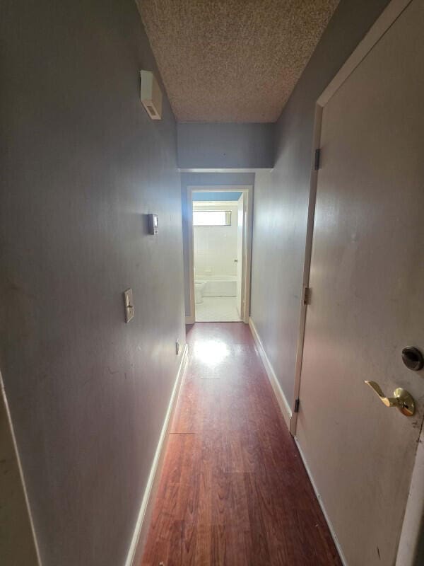 4580 Discovery Ln Unit 23, West Palm Beach, FL 33417 - hallway with a textured ceiling, wood finished floors, and baseboards