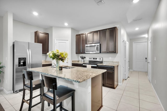 6340 Sailpointe Ln, West Palm Beach, FL 33413 - kitchen with stainless steel appliances, dark brown cabinetry, light tile patterned floors, a breakfast bar area, and recessed lighting