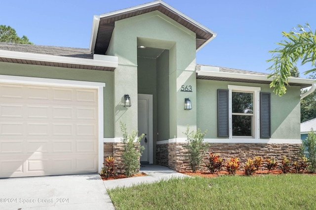 181 Ferguson St SE, Palm Bay, FL 32909 - view of front facade with stone siding, stucco siding, a garage, a shingled roof, and driveway