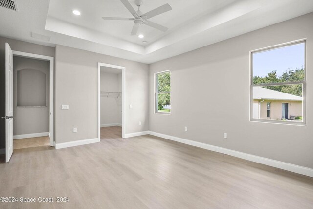 181 Ferguson St SE, Palm Bay, FL 32909 - unfurnished bedroom with a raised ceiling, light wood-type flooring, recessed lighting, baseboards, and a walk in closet