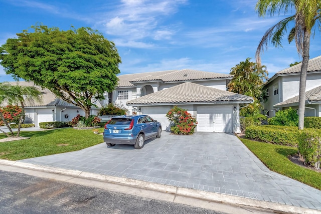 11650 Briarwood Cir Unit 2, Boynton Beach, FL 33437 - view of front of house with a tiled roof, a front yard, stucco siding, an attached garage, and driveway