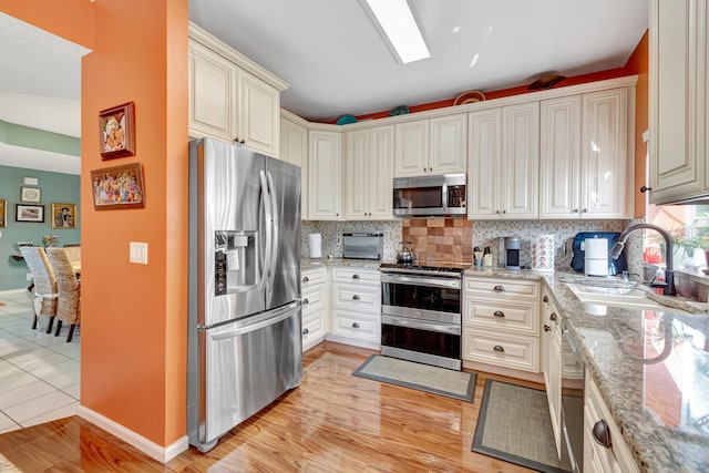 11650 Briarwood Cir Unit 2, Boynton Beach, FL 33437 - kitchen with appliances with stainless steel finishes, a sink, backsplash, baseboards, and light stone counters