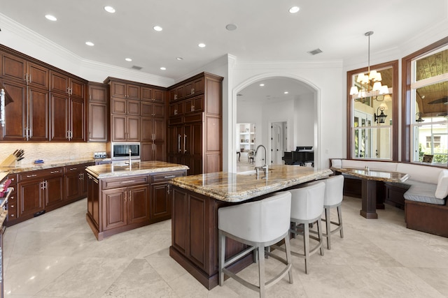9212 Perth Rd, Lake Worth, FL 33467 - kitchen featuring a center island with sink, a chandelier, crown molding, light stone counters, and arched walkways