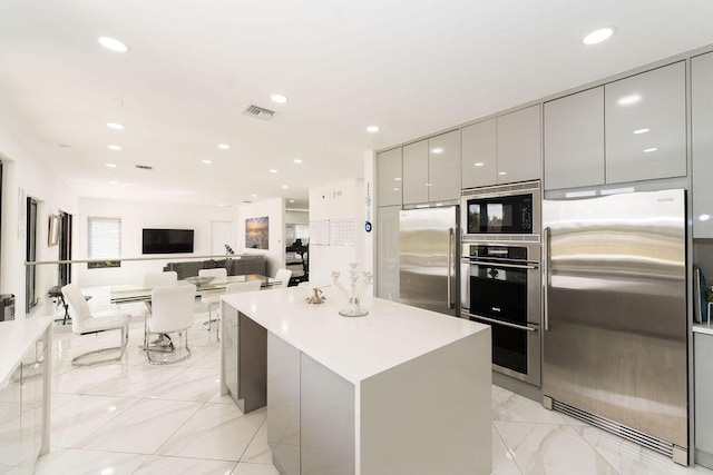 9475 Equus Cir, Boynton Beach, FL 33472 - kitchen with stainless steel appliances, modern cabinets, gray cabinetry, light marble finish floors, and a kitchen island