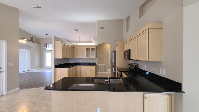 5170 NW Aljo Ct, Port Saint Lucie, FL 34986 - kitchen with light brown cabinetry, stainless steel appliances, arched walkways, a sink, and high vaulted ceiling