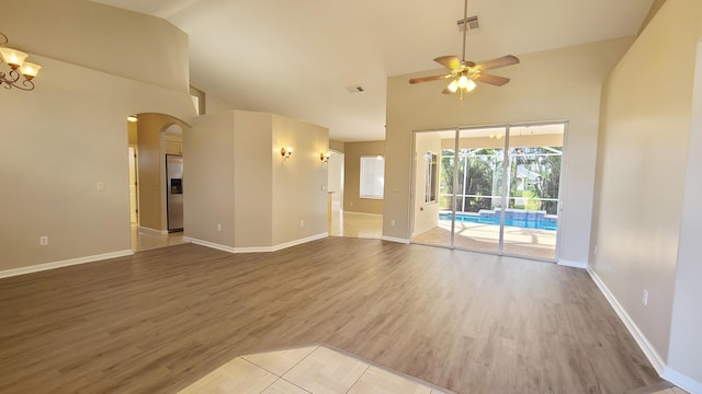 5170 NW Aljo Ct, Port Saint Lucie, FL 34986 - unfurnished living room featuring arched walkways, high vaulted ceiling, a ceiling fan, wood finished floors, and baseboards