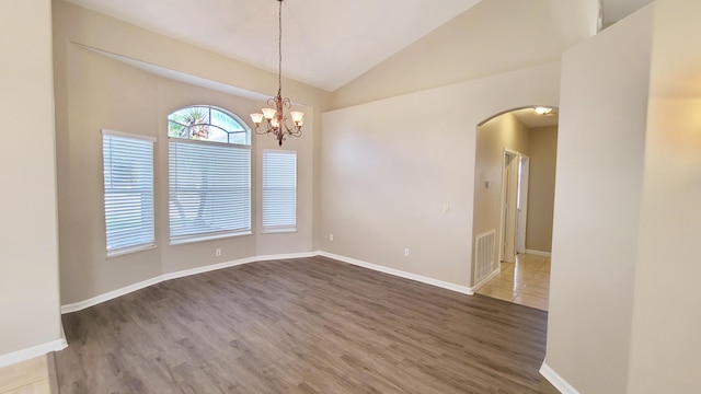 5170 NW Aljo Ct, Port Saint Lucie, FL 34986 - spare room with arched walkways, lofted ceiling, wood finished floors, a chandelier, and baseboards