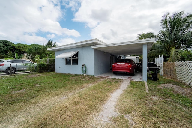 1214 Peak Rd, Lantana, FL 33462 - view of home's exterior featuring dirt driveway, stucco siding, and a carport