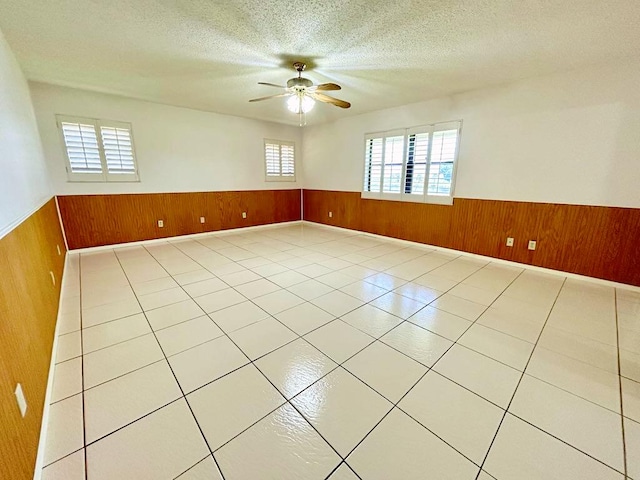 2657 River Rd, Moore Haven, FL 33471 - empty room with wainscoting, wooden walls, ceiling fan, a textured ceiling, and tile patterned floors