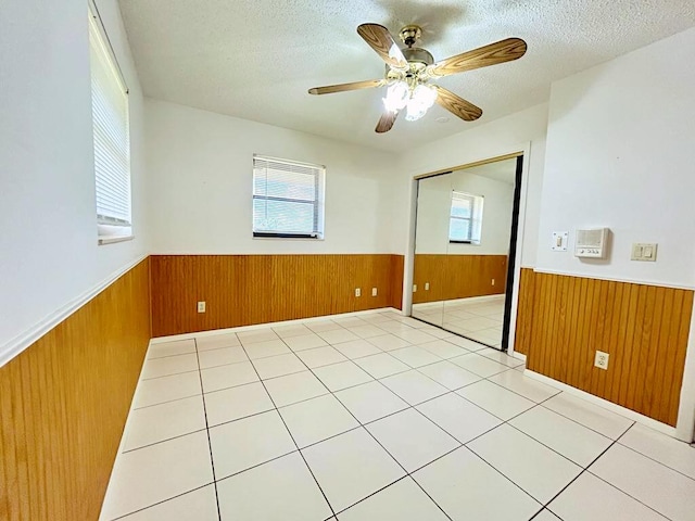 2657 River Rd, Moore Haven, FL 33471 - spare room featuring a wainscoted wall, wooden walls, healthy amount of natural light, a textured ceiling, and ceiling fan