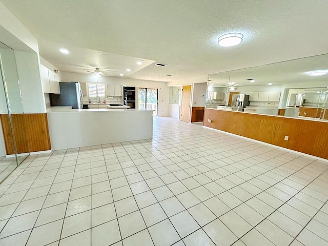 2657 River Rd, Moore Haven, FL 33471 - kitchen featuring a ceiling fan, open floor plan, a peninsula, freestanding refrigerator, and white cabinets