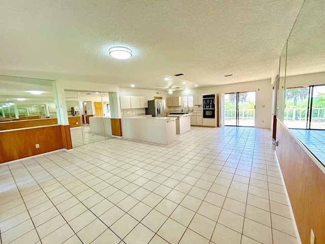2657 River Rd, Moore Haven, FL 33471 - kitchen with open floor plan, stainless steel fridge, light tile patterned floors, a textured ceiling, and light countertops