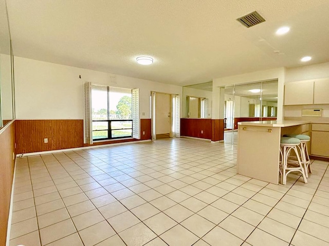 2657 River Rd, Moore Haven, FL 33471 - kitchen featuring a wainscoted wall, a breakfast bar, light countertops, a textured ceiling, and light tile patterned floors