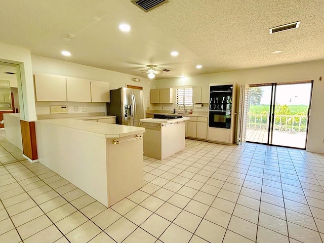 2657 River Rd, Moore Haven, FL 33471 - kitchen with stainless steel fridge with ice dispenser, light countertops, a textured ceiling, light tile patterned flooring, and recessed lighting