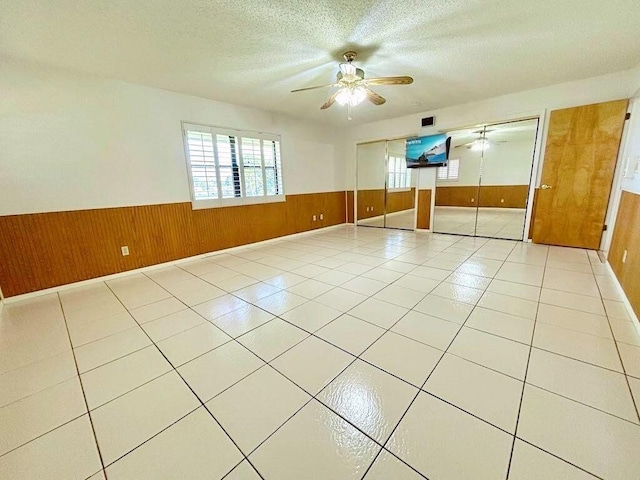 2657 River Rd, Moore Haven, FL 33471 - empty room with wainscoting, wooden walls, ceiling fan, a textured ceiling, and light tile patterned floors