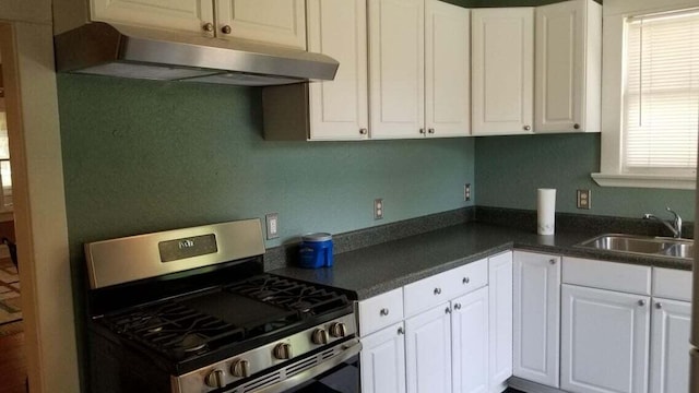 1512 Florida Ave Unit 1/2, West Palm Beach, FL 33401 - kitchen with stainless steel gas range, under cabinet range hood, a sink, dark countertops, and white cabinetry