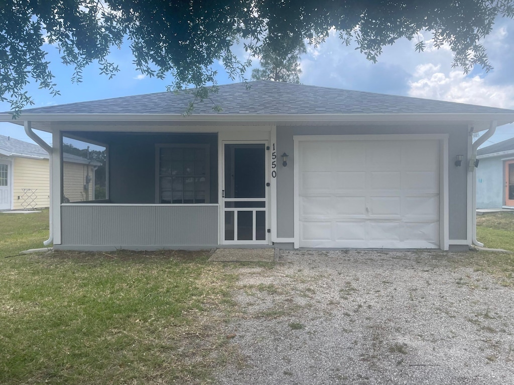 1550 17th Ct SW, Vero Beach, FL 32962 - view of front of house with roof with shingles, a garage, driveway, and a front lawn