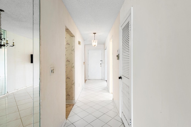 5606 Via Delray Unit B, Delray Beach, FL 33484 - hallway featuring a chandelier, a textured ceiling, light tile patterned floors, and baseboards