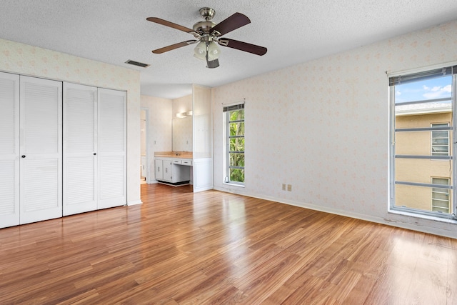 5606 Via Delray Unit B, Delray Beach, FL 33484 - unfurnished bedroom featuring wallpapered walls, light wood-type flooring, a textured ceiling, a closet, and baseboards