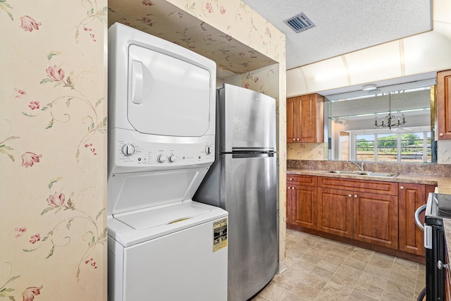 5606 Via Delray Unit B, Delray Beach, FL 33484 - laundry area with stacked washing machine and dryer, wallpapered walls, a chandelier, and a textured ceiling