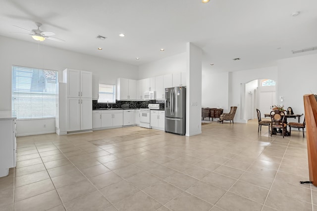 7703 Caprio Dr, Boynton Beach, FL 33472 - kitchen with white appliances, light tile patterned floors, a ceiling fan, arched walkways, and tasteful backsplash