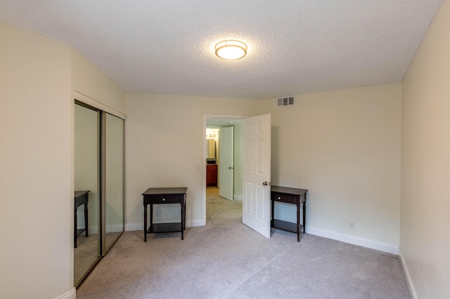 103 Weybridge C Cir Unit C, Royal Palm Beach, FL 33411 - unfurnished bedroom featuring light colored carpet, a textured ceiling, and a closet