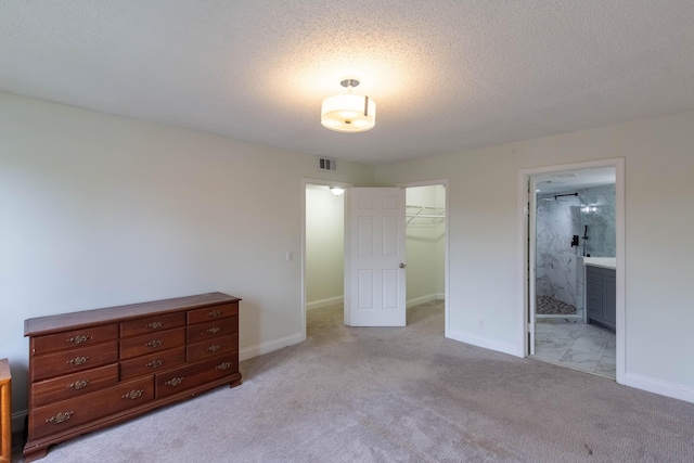 103 Weybridge C Cir Unit C, Royal Palm Beach, FL 33411 - unfurnished bedroom with light colored carpet, a walk in closet, a closet, ensuite bathroom, and a textured ceiling