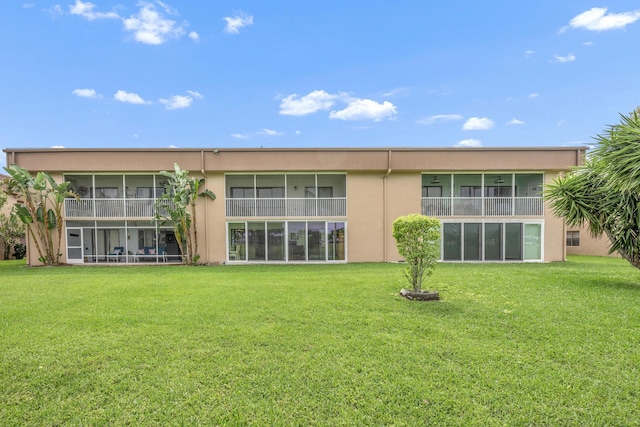 112 Piedmont C, Delray Beach, FL 33484 - rear view of house with stucco siding, a sunroom, and a yard