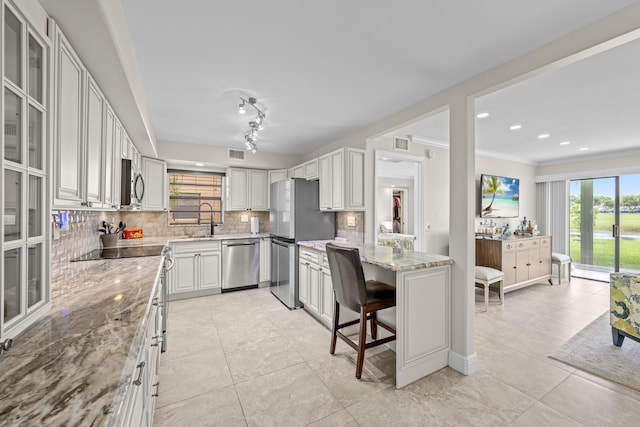 112 Piedmont C, Delray Beach, FL 33484 - kitchen featuring appliances with stainless steel finishes, tasteful backsplash, light stone countertops, light tile patterned flooring, and glass insert cabinets