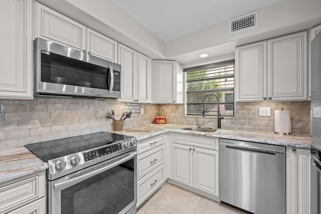 112 Piedmont C, Delray Beach, FL 33484 - kitchen featuring appliances with stainless steel finishes, light tile patterned flooring, light stone countertops, and tasteful backsplash