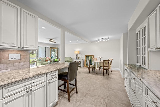 112 Piedmont C, Delray Beach, FL 33484 - kitchen with backsplash, open floor plan, light stone countertops, white cabinetry, and recessed lighting
