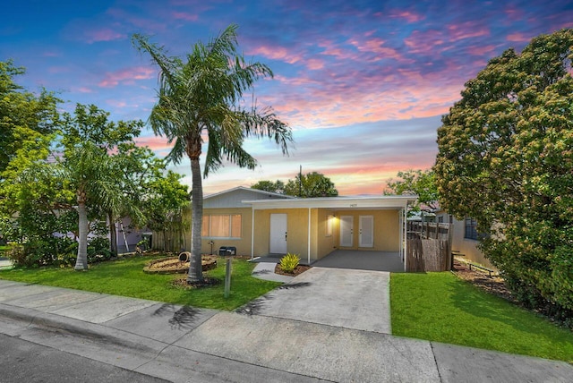1405 N J Ter, Lake Worth Beach, FL 33460 - ranch-style house featuring french doors, a front lawn, a carport, concrete driveway, and stucco siding